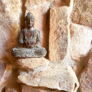 A statue of Buddha on a rock wall.
