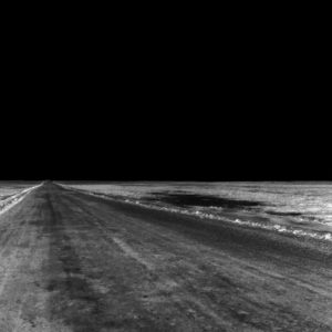 A black-and-white image of a road going to a point in the darkness.